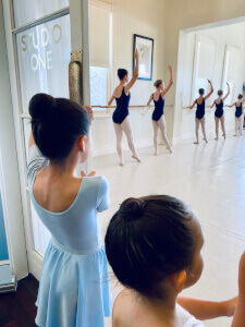 Two young students watch senior students at the barre in Studio One